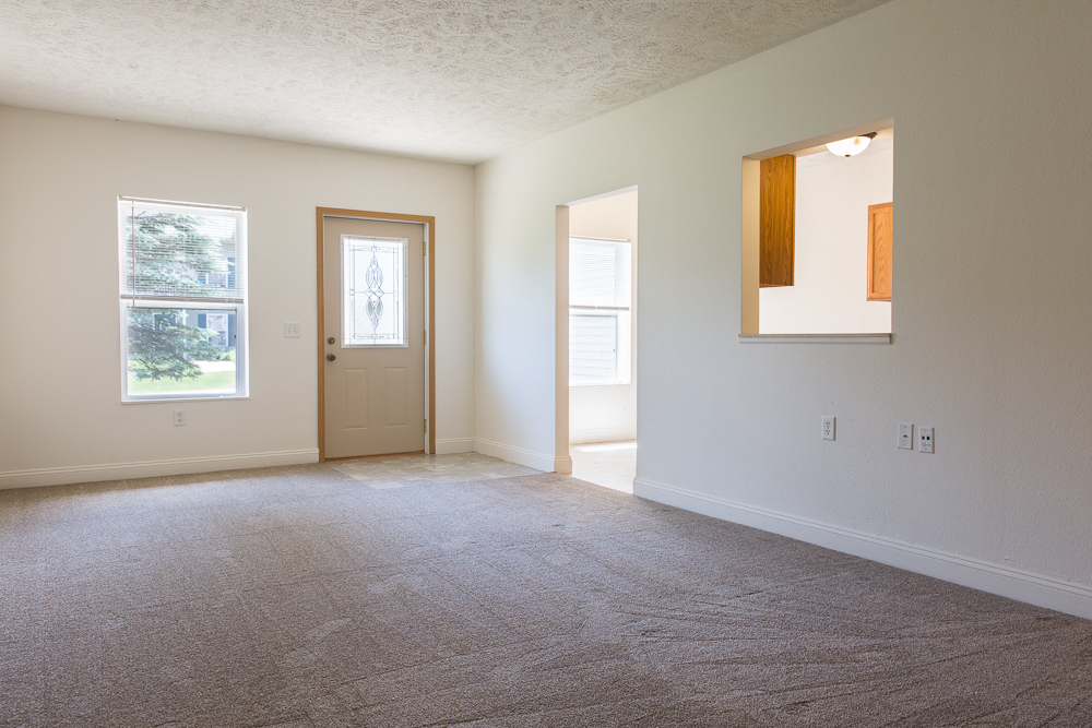an empty living room with a door and a window