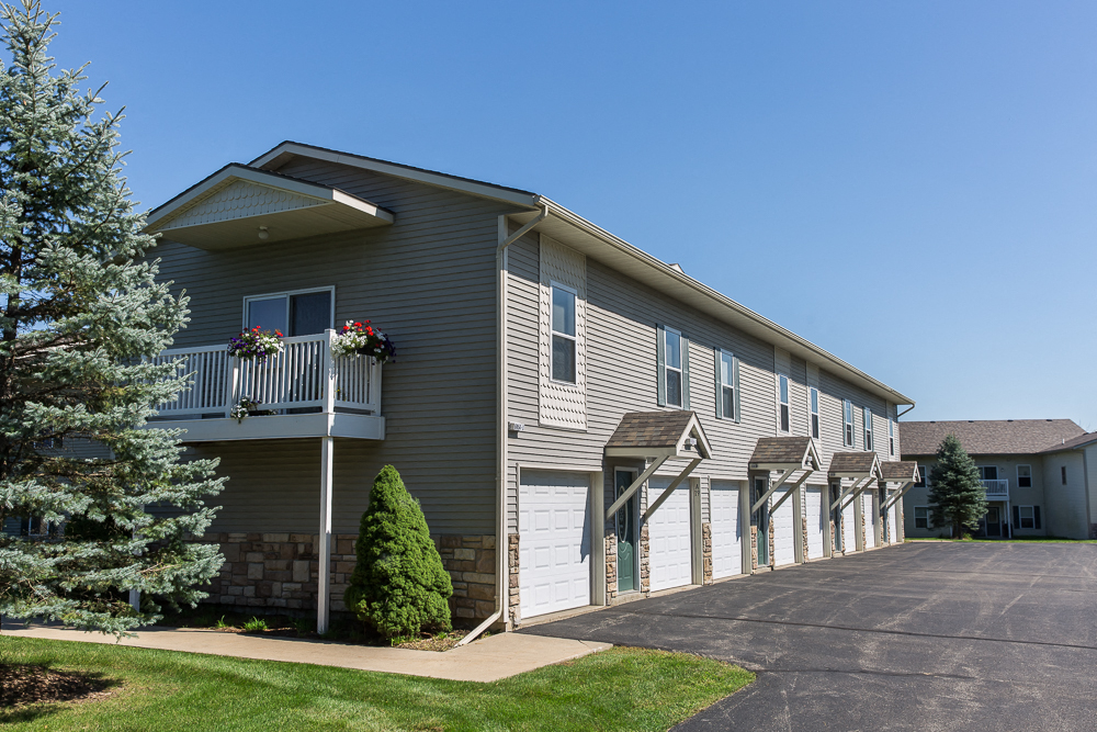a gray house with white doors and a driveway