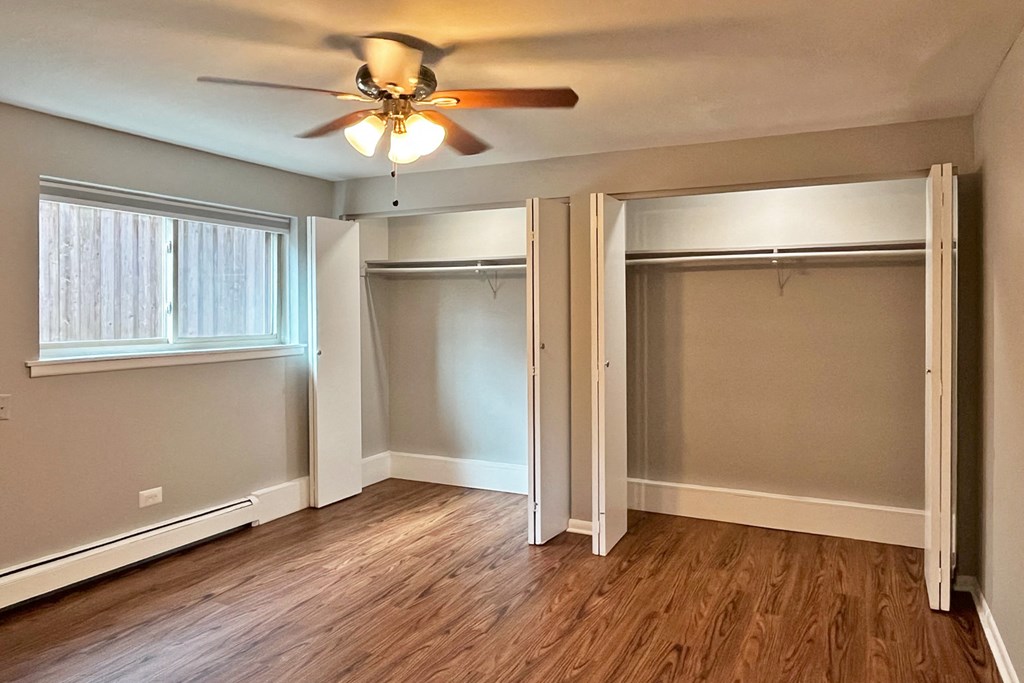 A room with a ceiling fan and sliding glass doors.