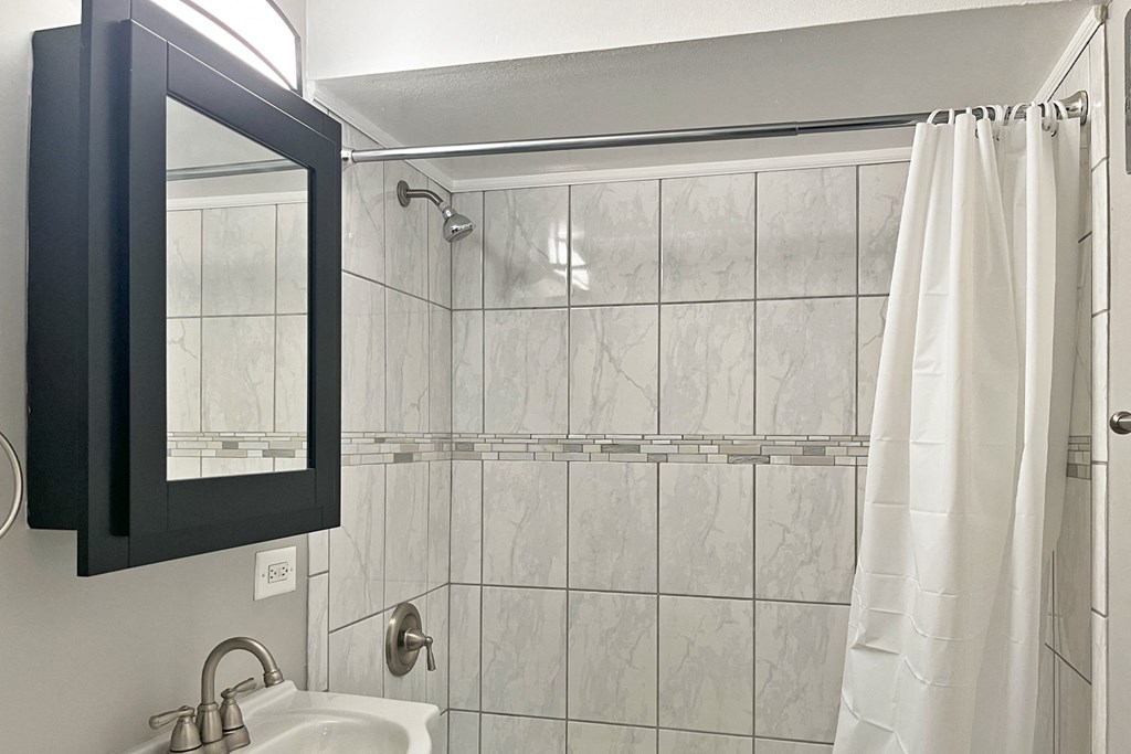 A white shower curtain hangs in a bathroom.