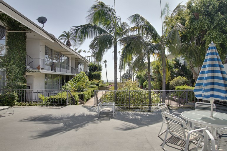 a patio with chairs and an umbrella in front of a building