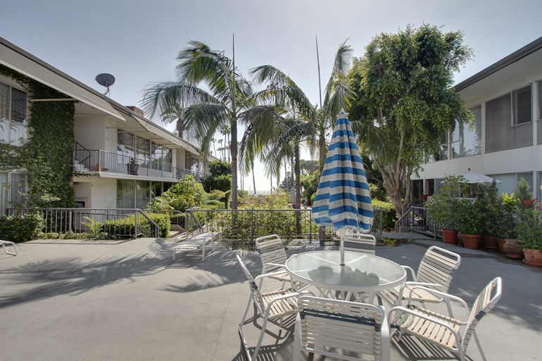 a patio with tables and chairs and a blue and white umbrella