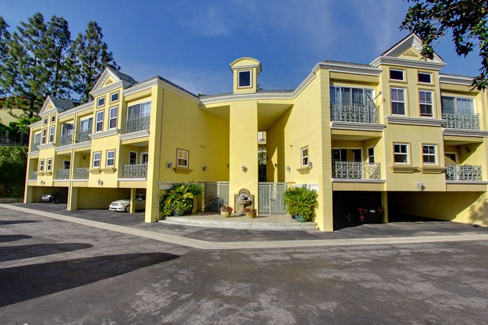 a large yellow apartment building with a parking lot