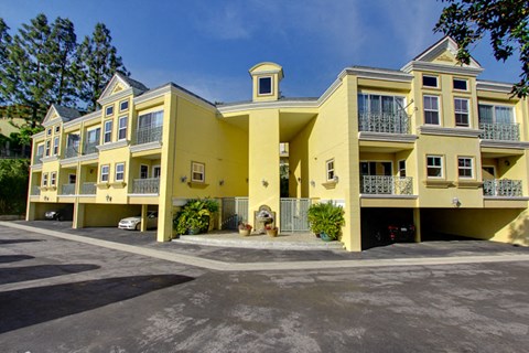 a large yellow apartment building with a parking lot