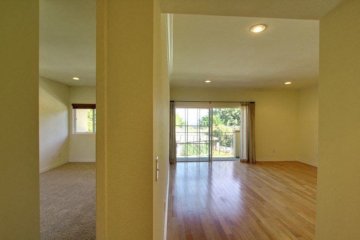 an empty living room with wood floors and a sliding glass door