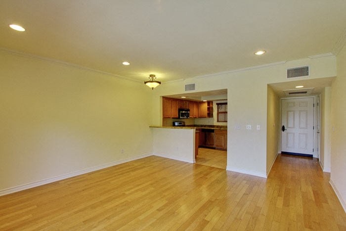an empty living room and kitchen with a wood floor