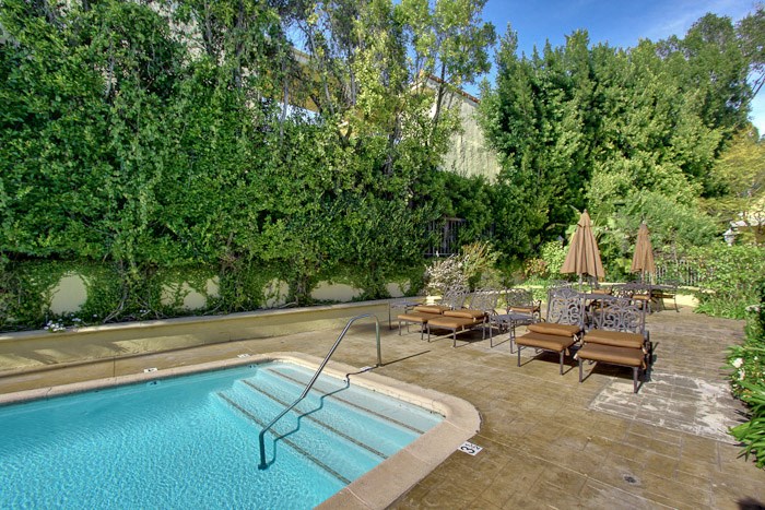 a swimming pool with tables and chairs next to it