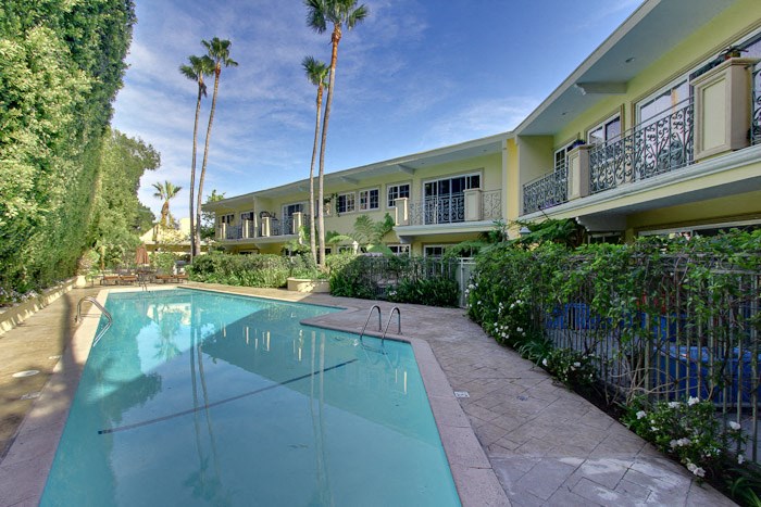 a large pool in front of a house with palm trees