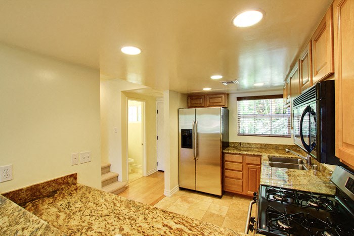 a kitchen with granite counter tops and a stainless steel refrigerator
