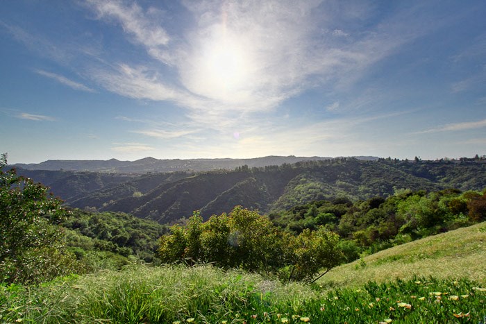 a view of the valley and mountains from a grassy hill