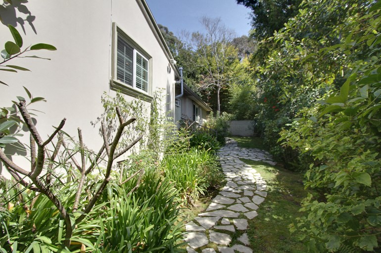 the path to the house is lined with plants and trees