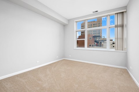 an empty living room with a large window and carpeting