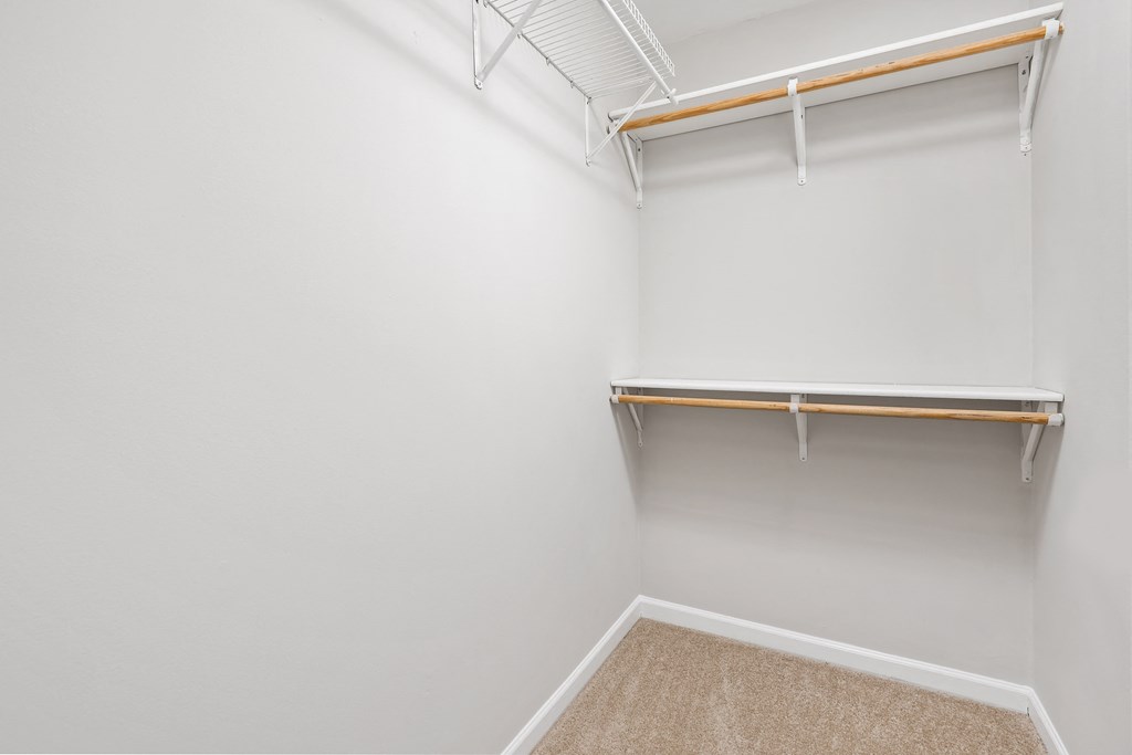 a walk in closet with white walls and a hanger rack on the wall