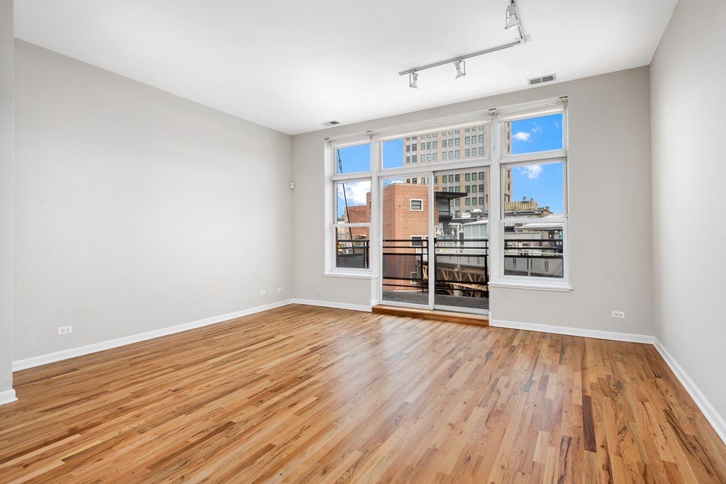 an empty living room with wood floors and a large window