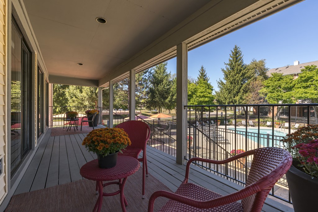 a patio with chairs and a pool in the background