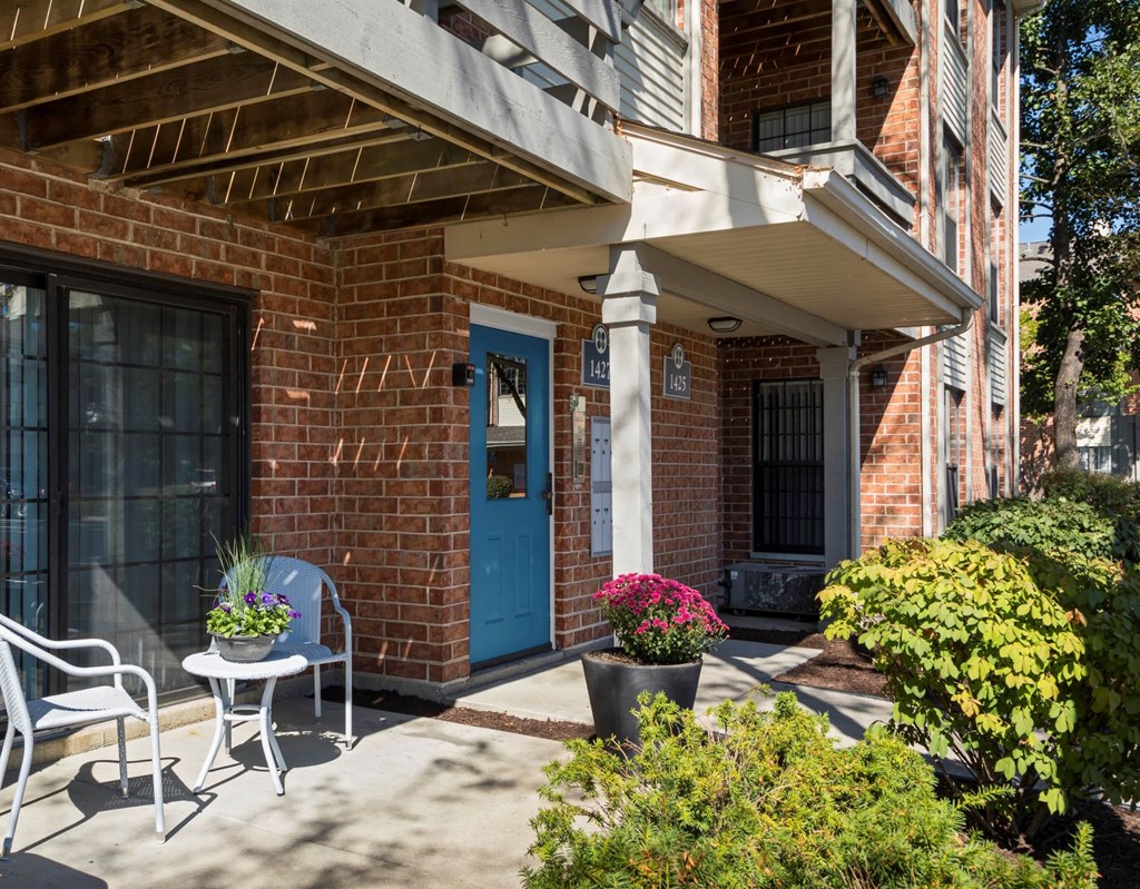 front porch with chairs and flowers and a blue door