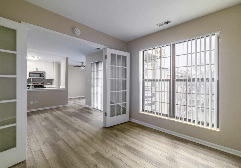 an empty living room with a large window and a kitchen