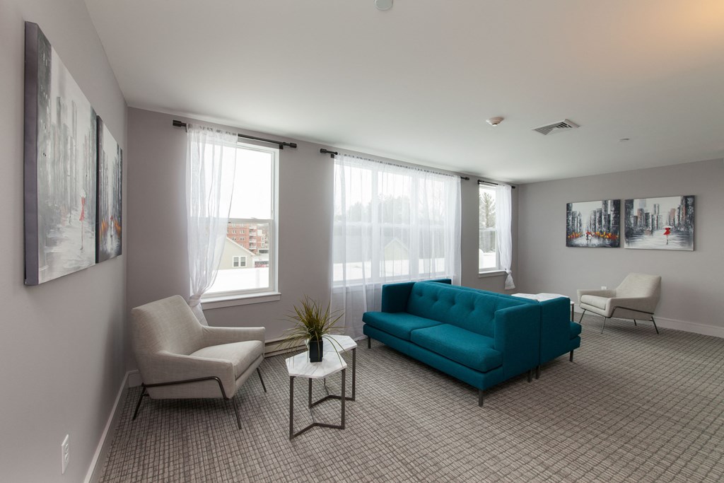 Sun-filled living space featuring teal accent furniture and large windows