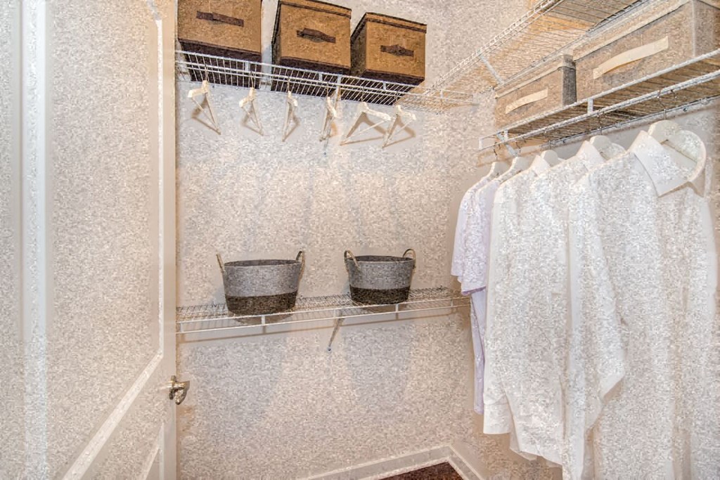 a walk in closet with two baskets and a rack of clothes