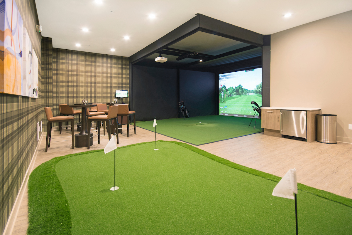 a golf room with a putting green and a tv on the wall