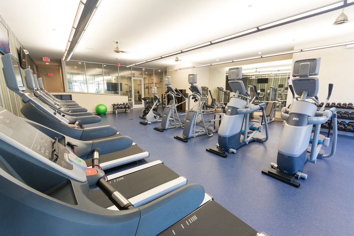 a gym with cardio equipment and weights on the floor