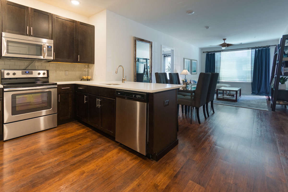 a kitchen and dining room with stainless steel appliances and wooden floors