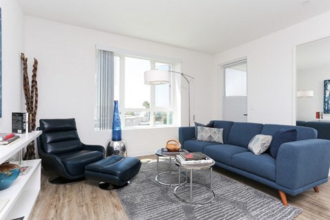 A living room with a blue couch and a black chair.