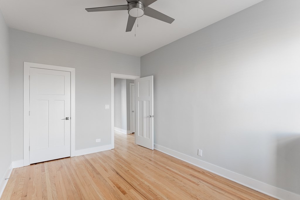 an empty room with wood floors and a ceiling fan