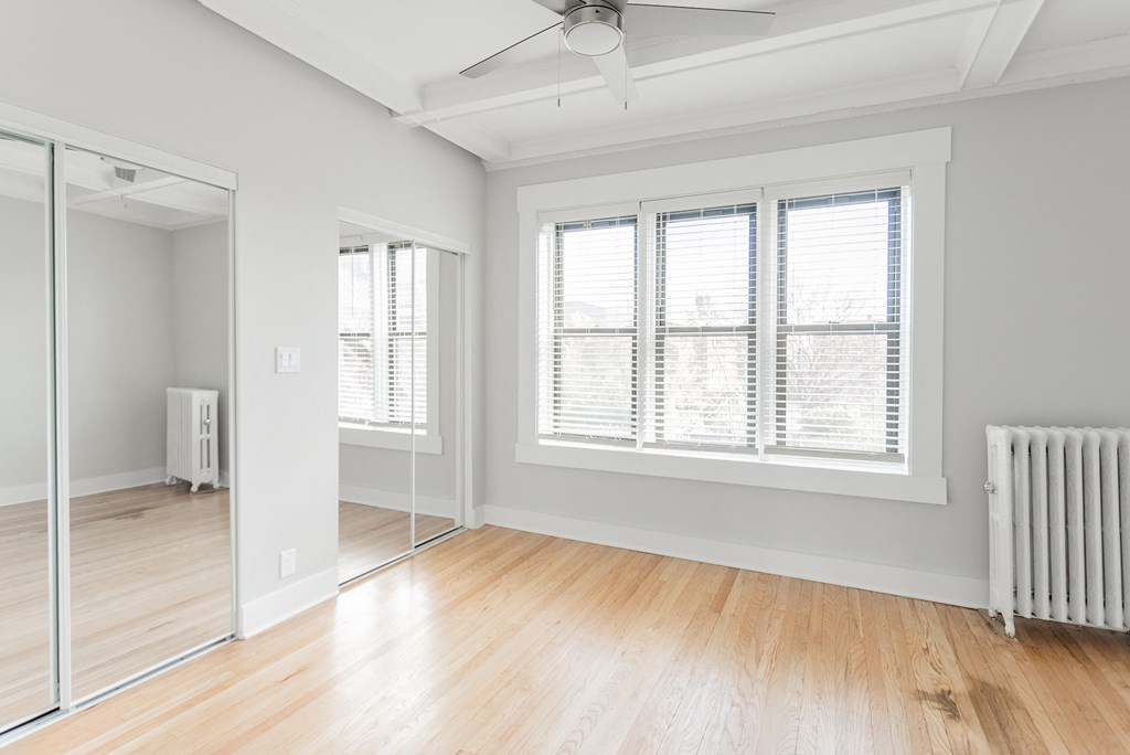 an empty room with wood floors and a large window