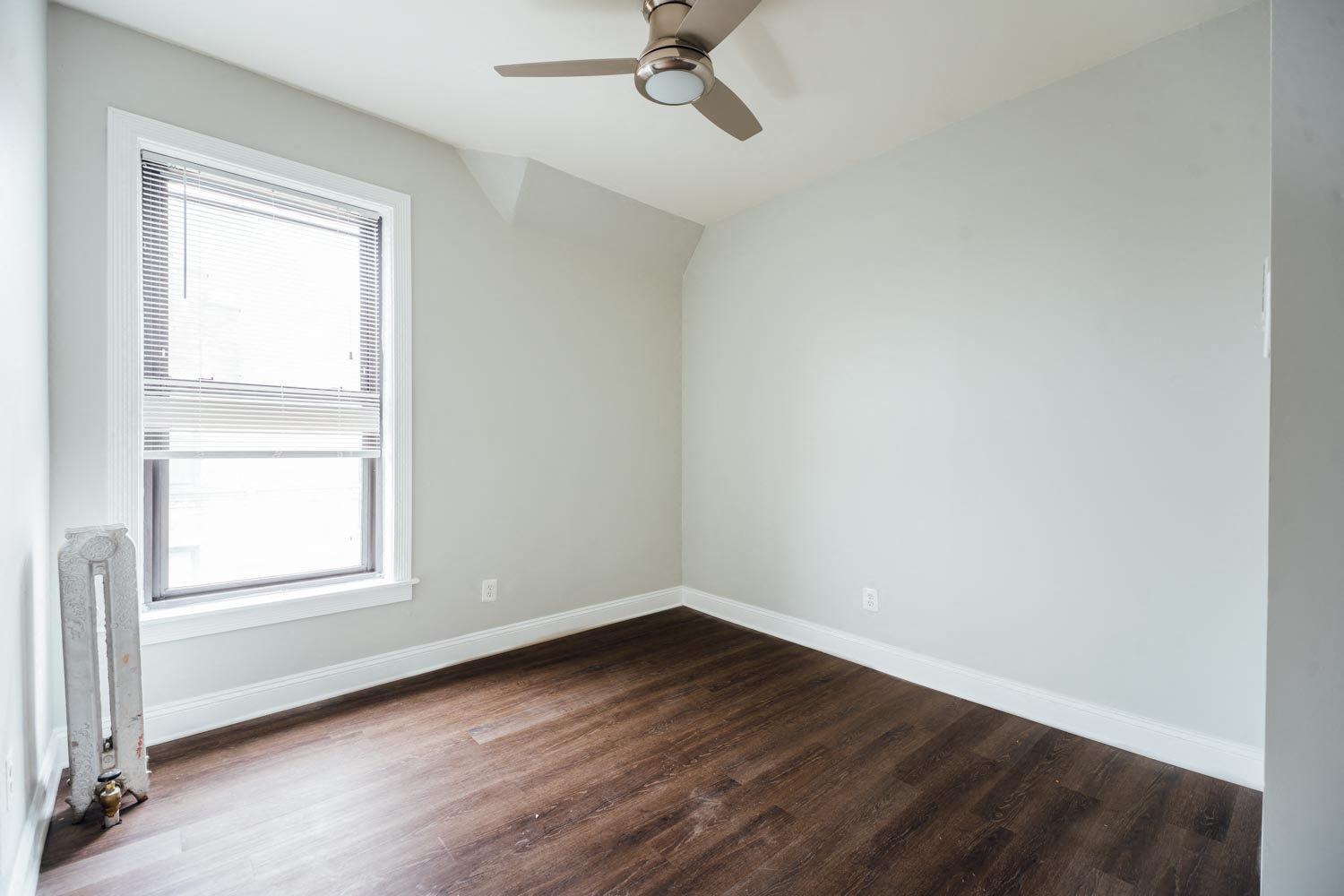 an empty room with wood floors and a ceiling fan