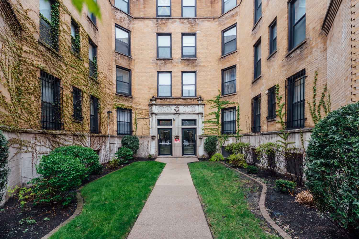 an apartment building with a sidewalk and lawn in front of it