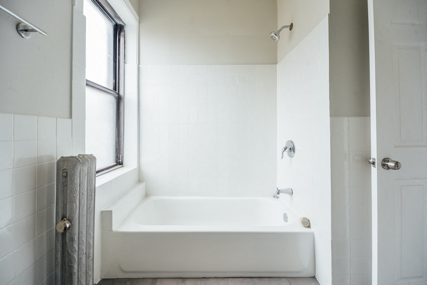 a white bathroom with a tub and a window