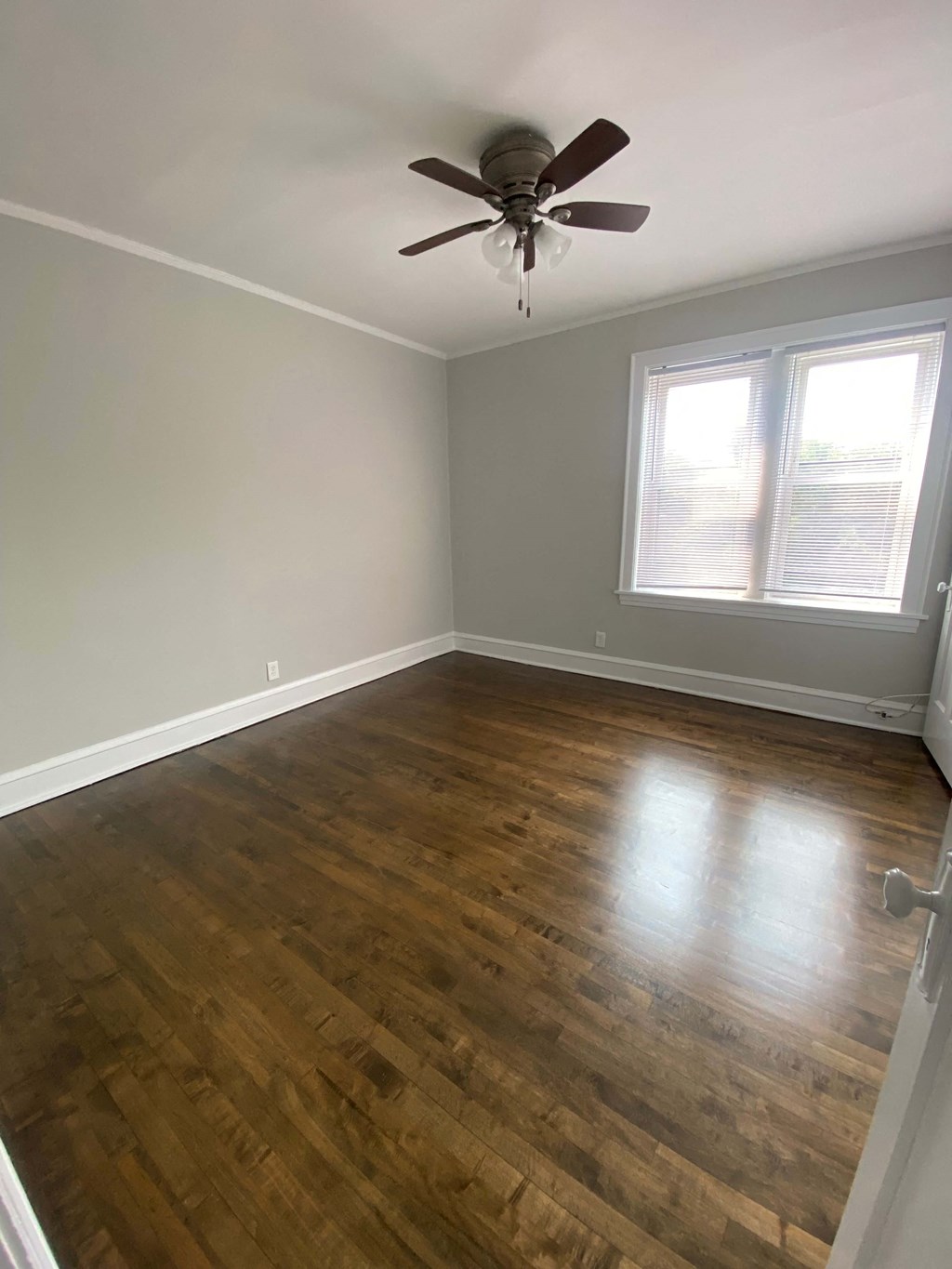 an empty room with wooden floors and a ceiling fan