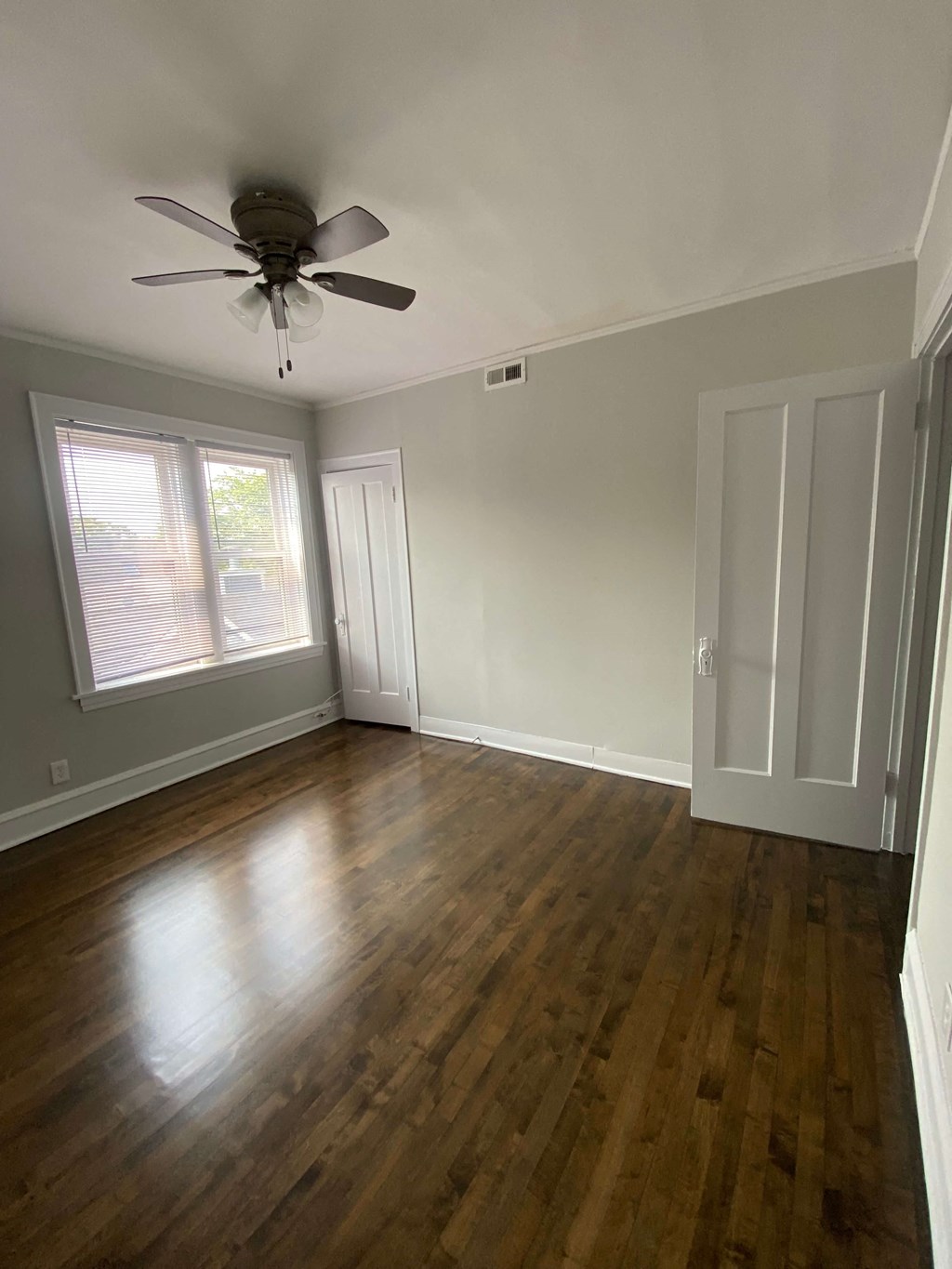 an empty living room with wooden floors and a ceiling fan