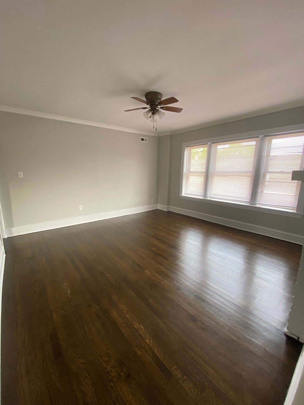 an empty living room with a ceiling fan and wood floors