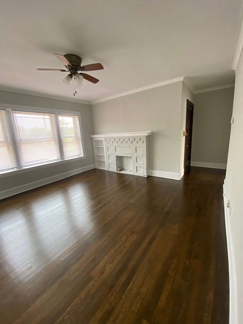 an empty living room with wooden floors and a ceiling fan