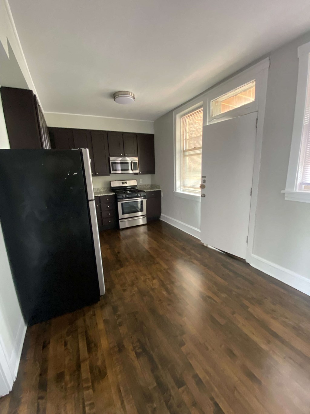 an empty kitchen with wooden floors and a refrigerator