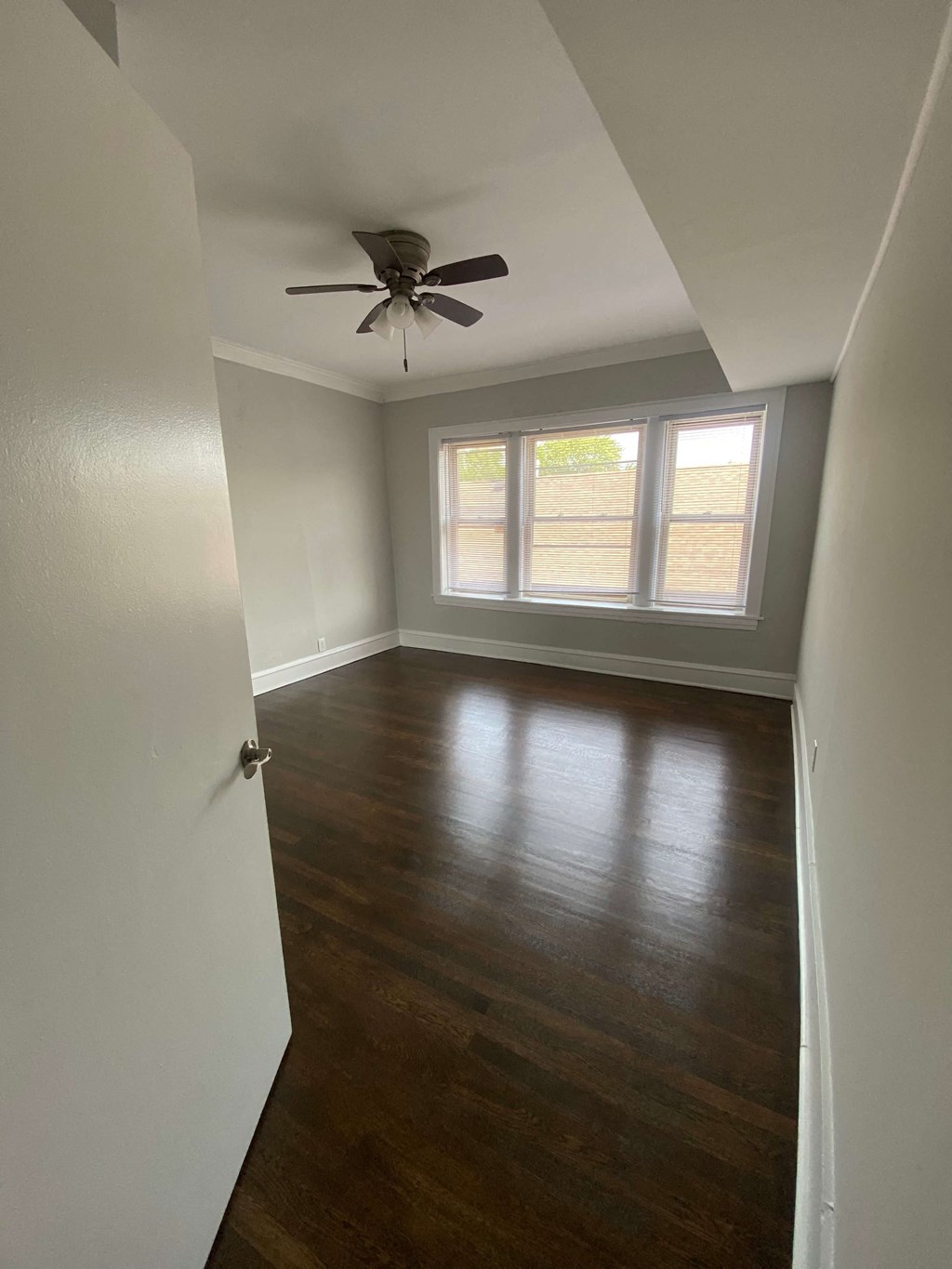 a empty room with wooden floors and a ceiling fan