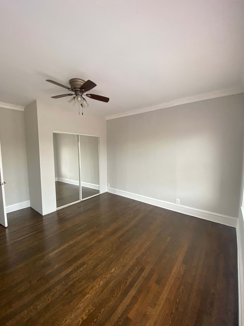 a empty living room with wood floors and a ceiling fan
