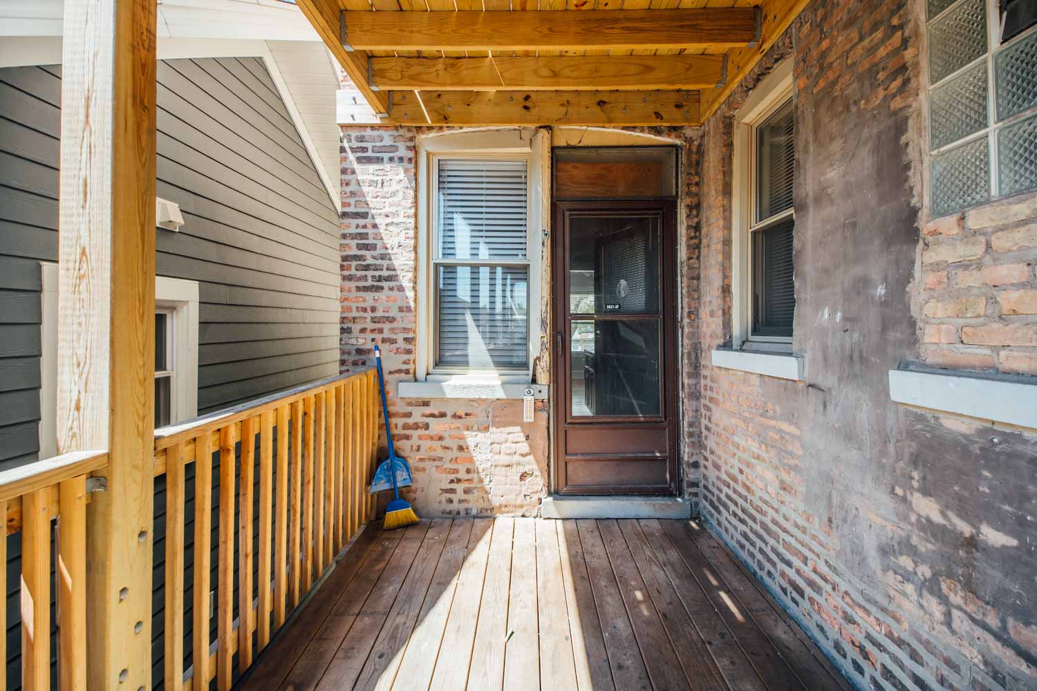 the front porch of a brick house with a wooden deck