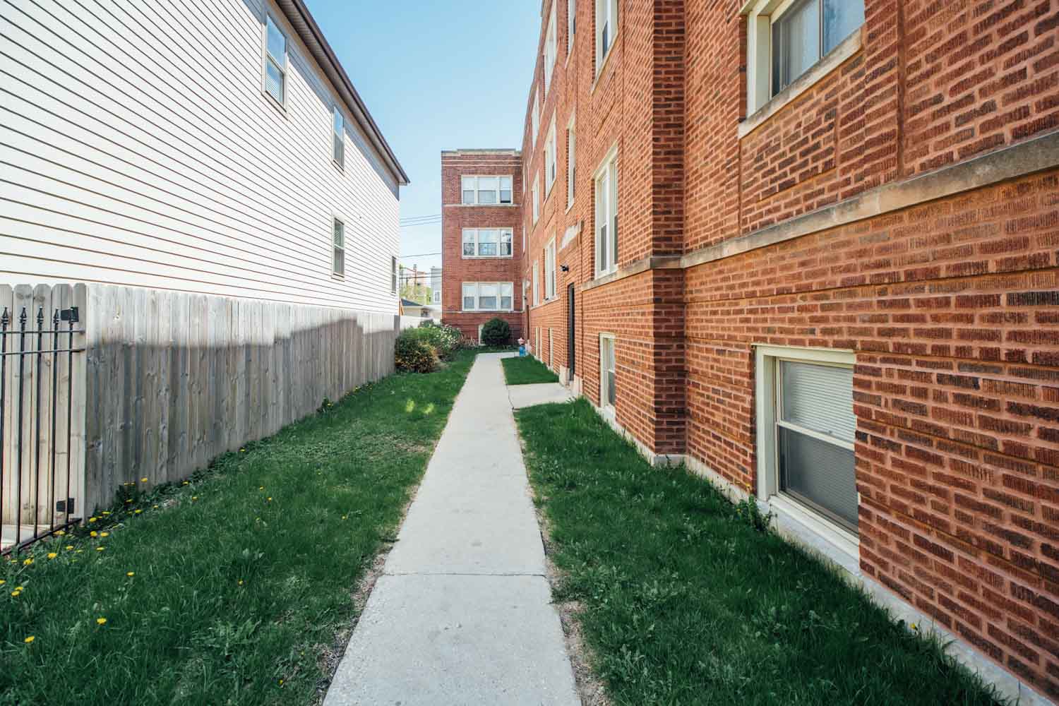 a walkway between two brick buildings with grass
