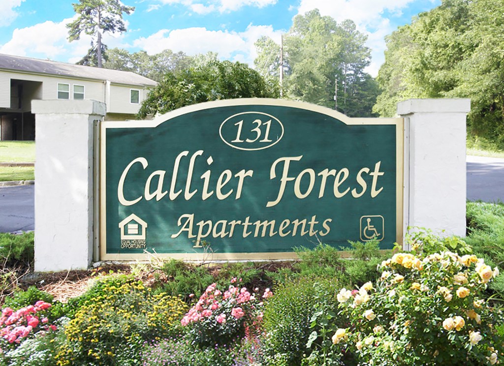 a green sign with white pillars and yellow and pink flowers in front of it