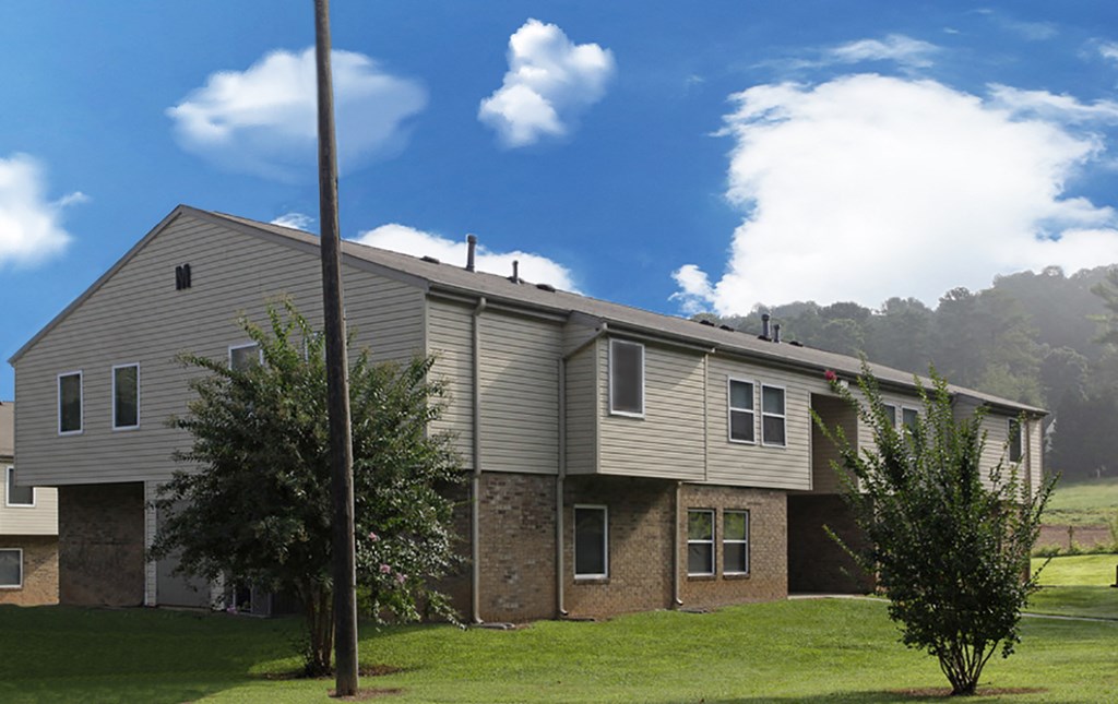 a house with a gray siding and a blue sky with white clouds