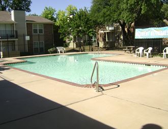 a pool with a fence around it and trees in the background
