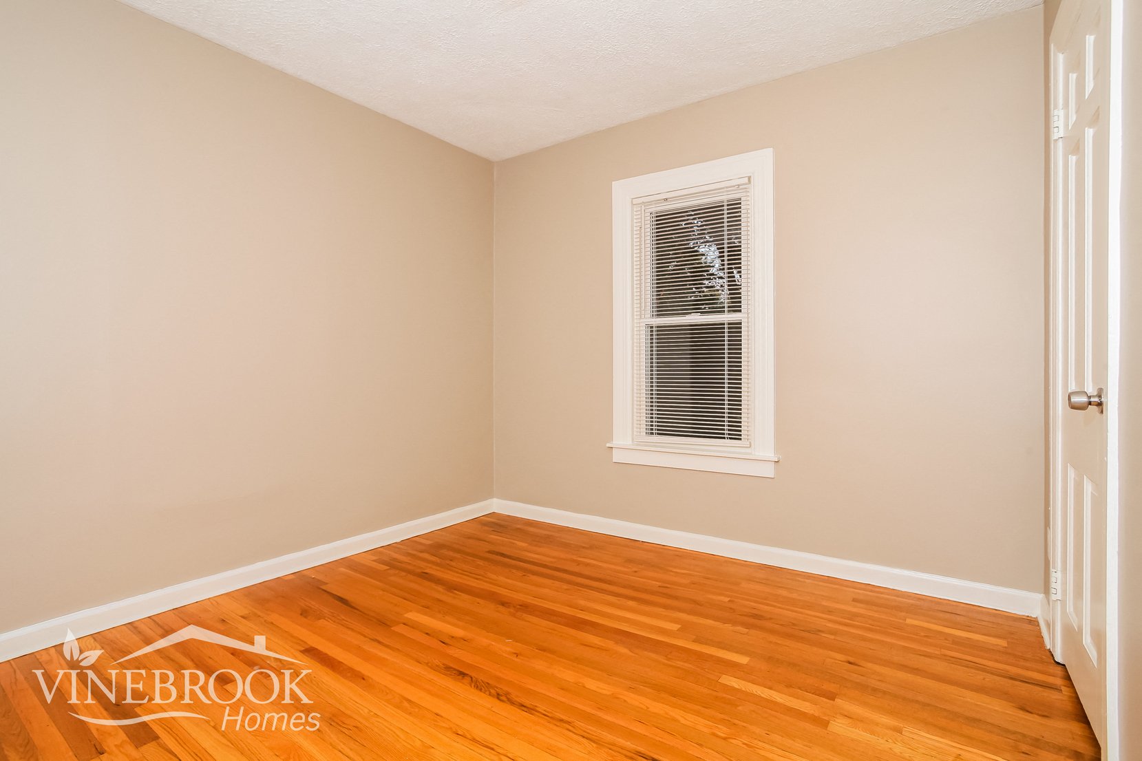 the living room of a home with wood floors and a window