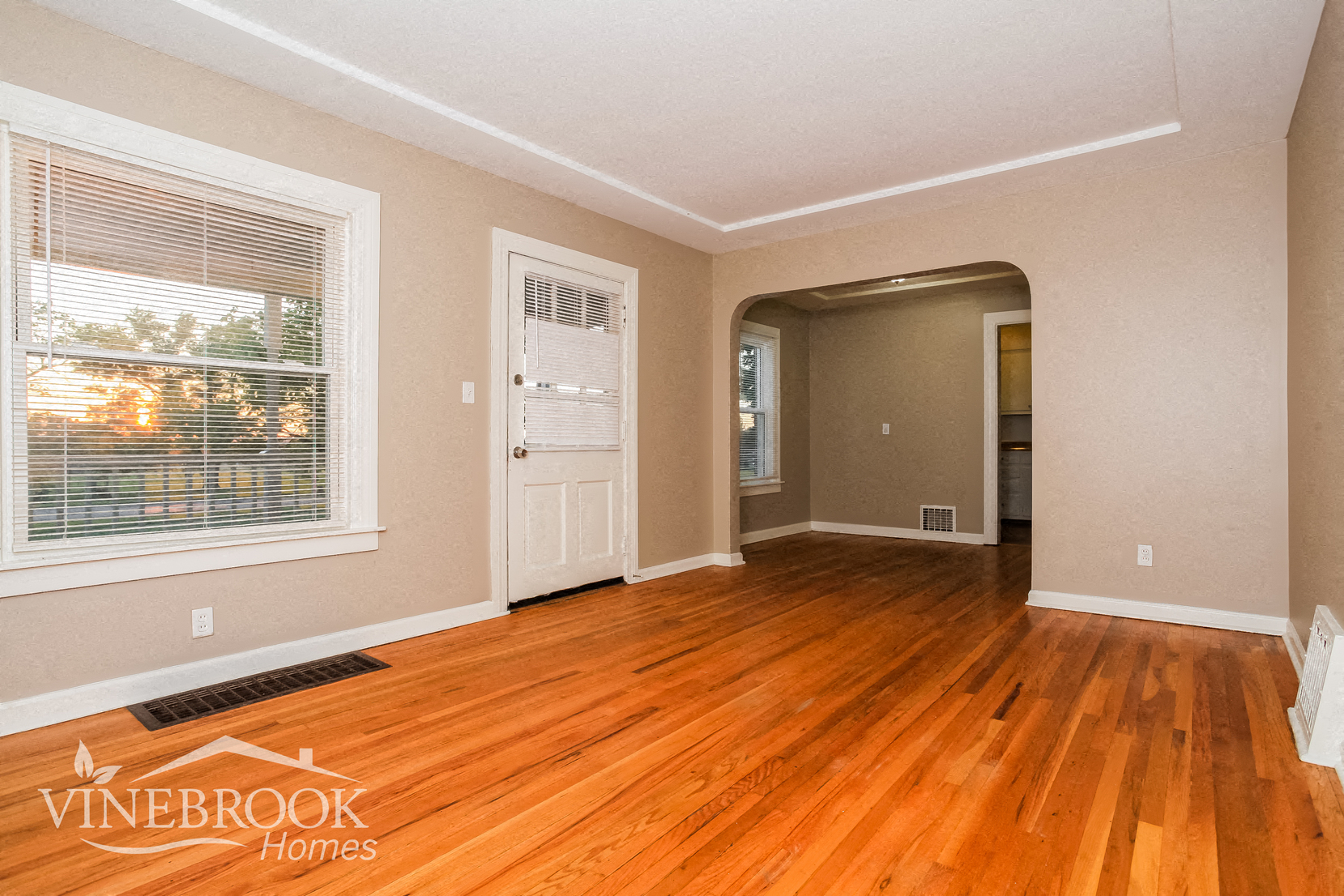 an empty living room with wood floors and a window