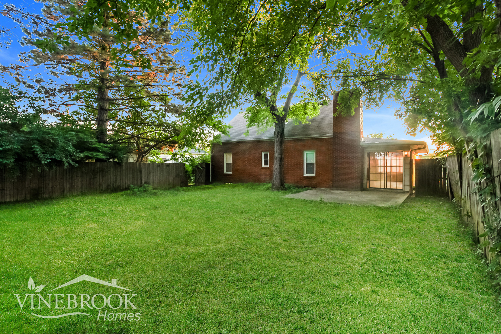 the backyard of a brick house with a yard and a fence