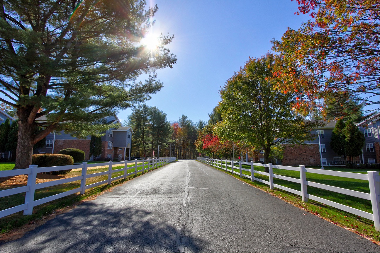 a street with a white fence and houses on the side of the road