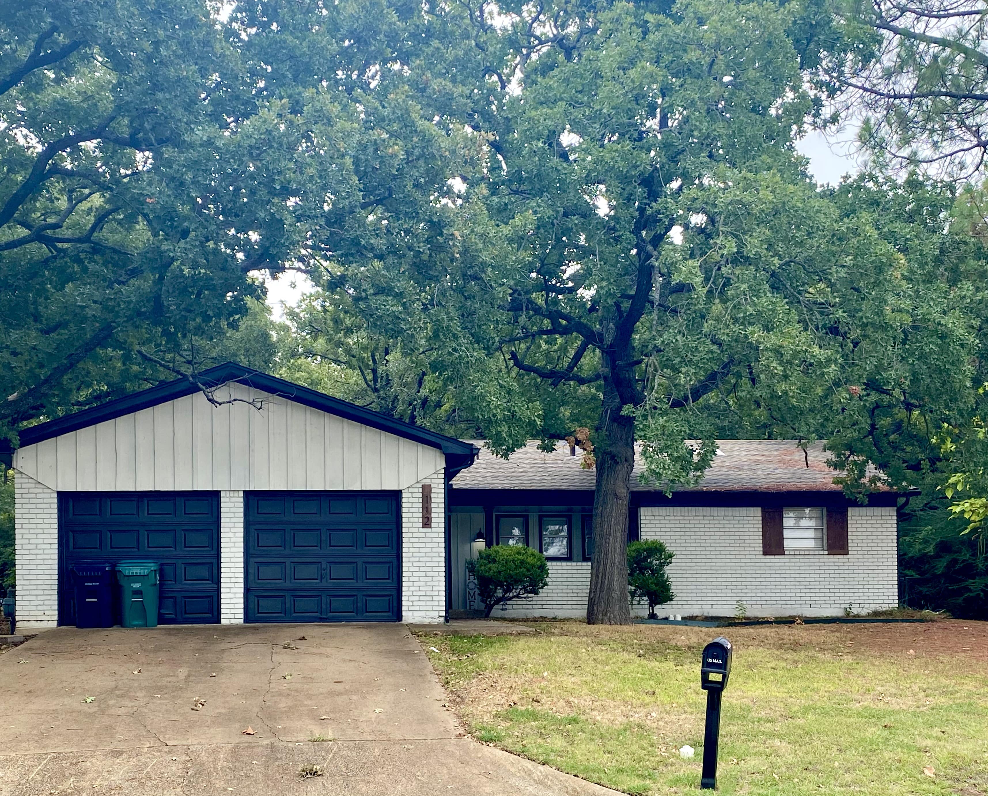 A house with a garage and a tree in front.