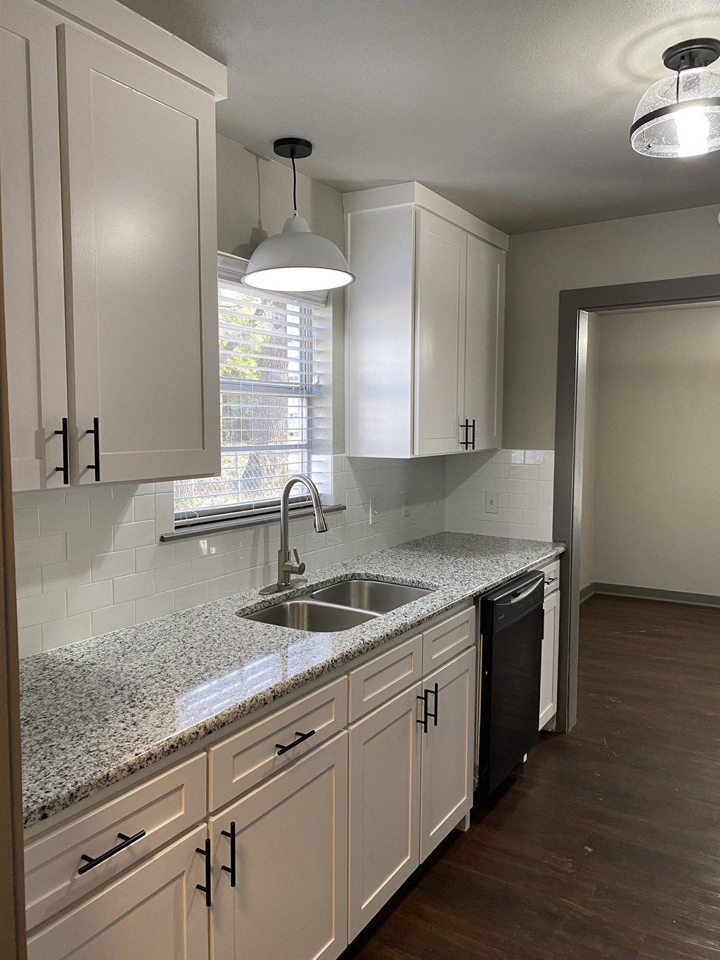 A kitchen with white cabinets and a granite countertop.